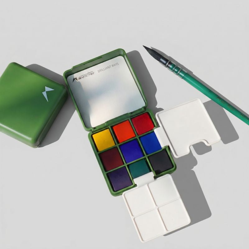 Open ArtMate Travel-Essential Art Set, a green 9-color watercolor box with fold-out mixing trays on a paper pad